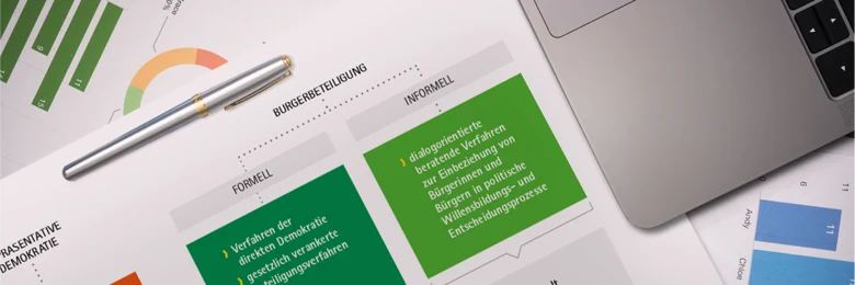 Auf einem Tisch liegen mehrere Zettel mit verschiedenen Grafiken und Tabellen sowie ein Laptop.