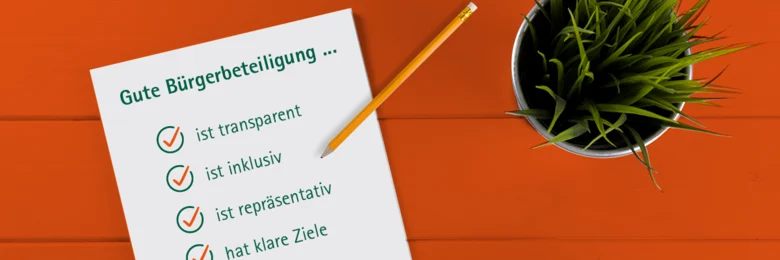 Auf einem orangen Tisch steht eine Topfpflanze und liegt ein Blatt Papier mit der Überschrift "Gute Bürgerbeteiligung..." und einer Aufzählungsliste.