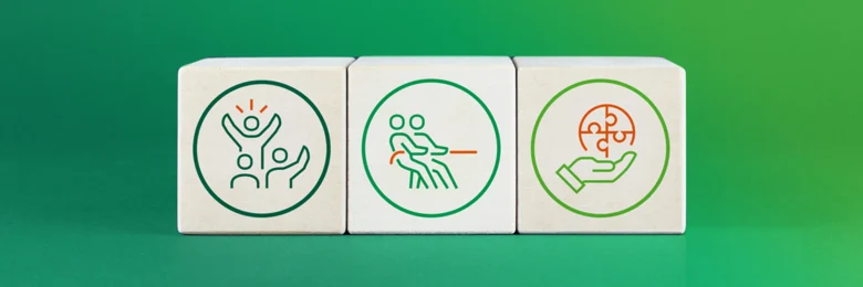 Vor einem grünen Hintergrund sind drei Holzbauklötze mit verschiedenen Icons abgebildet.