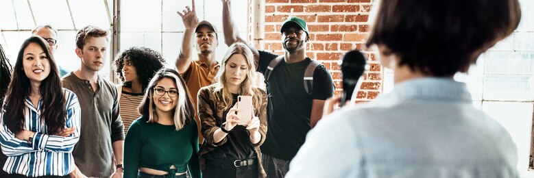 Über die Schultern einer Person ist eine Gruppe von jungen Menschen zu sehen.