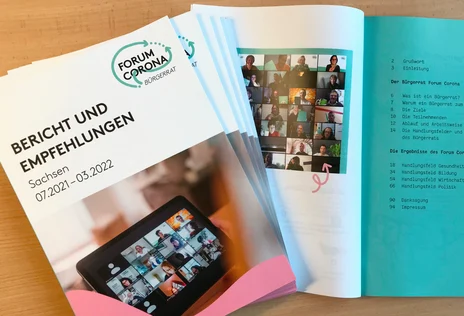 Diverse Exemplare der Broschüre zum "Forum Corona" liegen auf einem Tisch, eines von ihnen aufgeblättert.