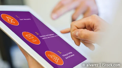 Eine Person hält ein Tablet in der Hand.