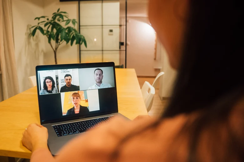 Über die Schulter einer Person ist ein Laptop zu sehen, auf dem die Videos des Moderationsteams, von Ministerpräsident Kretschmer und Demokratieministerin Meier angezeigt werden.