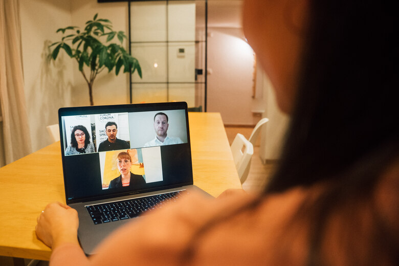 Über die Schulter einer Person ist ein Laptop zu sehen, auf dem die Videos des Moderationsteams, von Ministerpräsident Kretschmer und Demokratieministerin Meier angezeigt werden.