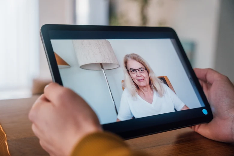 Eine Person hält ein Tablet in der Hand, auf dem das Video von Prof. Dr. Birgit Leyendecker zu sehen ist.