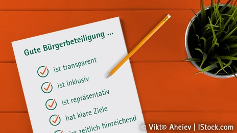 Vor einem orangen Hintergrund ist ein Zettel abgebildet, auf dem eine Checkliste mit dem Titel "Gute Bürgerbeteiligung..." dargestellt ist.