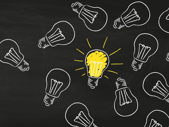 Auf einen schwarzen Hintergrund sind verschiedene Glühbirnen mit weißer Kreide gemalt, eine davon ist gelb ausgemalt.